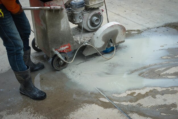 Foto lavoratore stradale che taglia l'asfalto, che lavora alla ricostruzione stradale, sezione bassa della persona che lavora