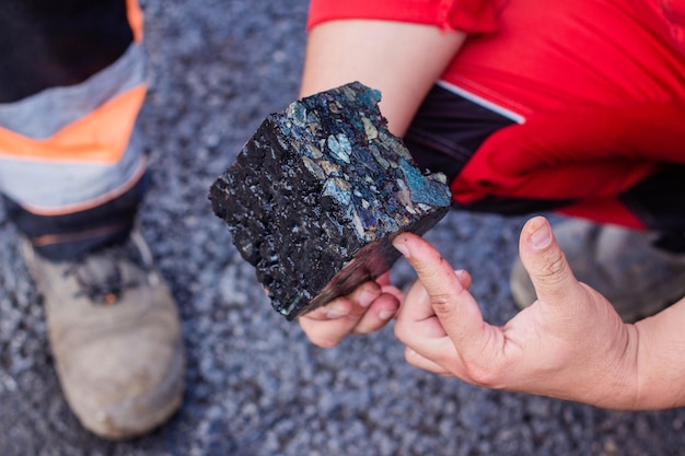 Road workers take a cube of asphalt