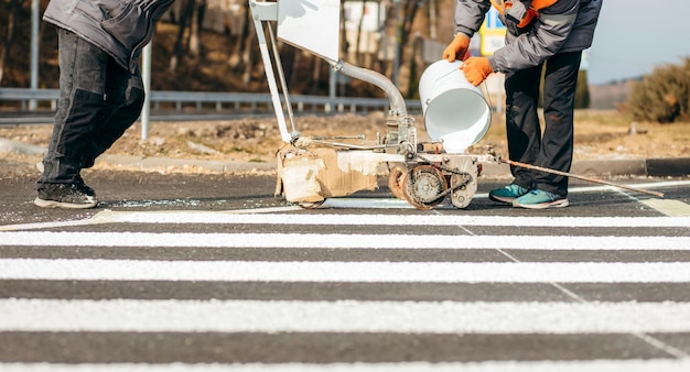 Road workers use scribing machines to painting pedestrian crosswalk on asphalt in the city