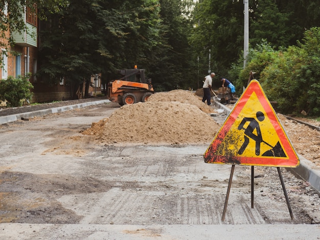 Cartello di lavori stradali sullo sfondo di una strada in costruzione