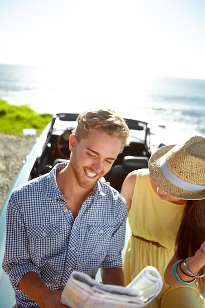 Roadtrip avontuur en koppel met kaart door oceaan op zomervakantie vakantie en weekendje weg op auto Reizende vrijheid en man en vrouw die papier lezen voor routebeschrijving navigatie en reis