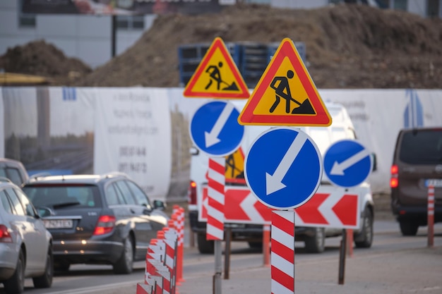 Roadworks warning traffic signs of construction work on city\
street and slowly moving cars