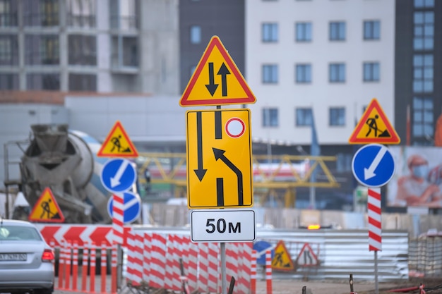 Roadworks warning traffic signs of construction work on city street and slowly moving cars