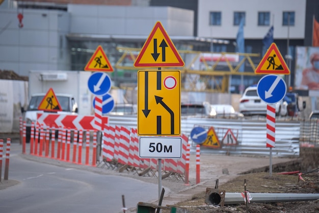 Roadworks warning traffic signs of construction work on city street and slowly moving cars