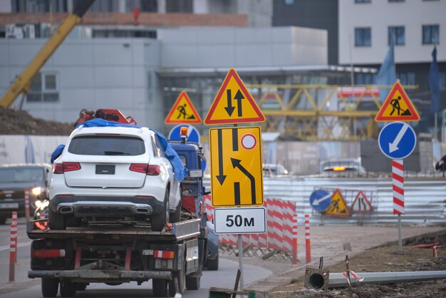 Foto lavori stradali che avvertono i segnali stradali dei lavori di costruzione sulle strade cittadine e delle auto che si muovono lentamente