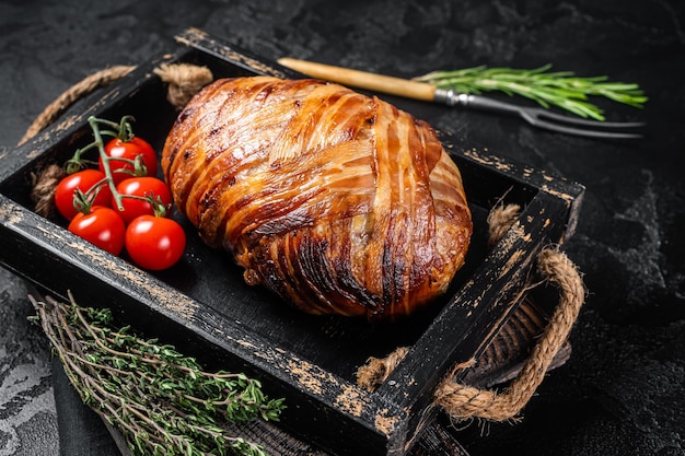 Roast bacon wrapped meatloaf meat loaf in a tray with herbs Black background Top view