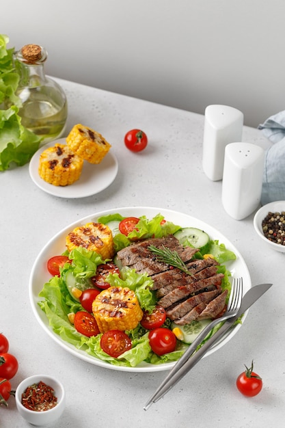 Photo roast beef salad on white plate and grey background salad meal with meat steak grilled corn and beef