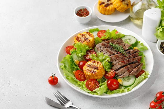 Photo roast beef salad on white plate and grey background salad meal with meat steak grilled corn and beef