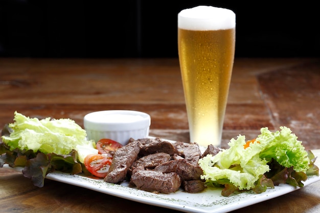 Roast beef with potatoes and salad and a glass of beer