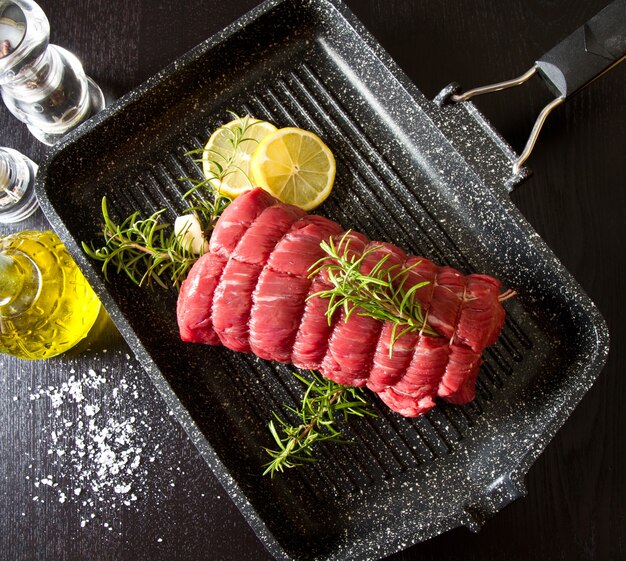 Photo roast of beef with rosemary on plate pot on black