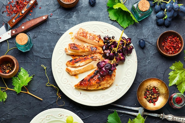 Roast chicken breast with grapes.Summer BBQ.Barbecued chicken meat.