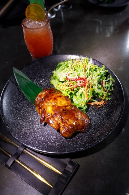 Roast duck with salad on a black plate