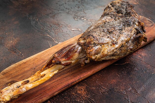 Roast lamb leg meat with herbs and spices on a cutting board Dark background Top view