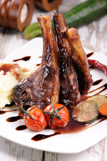 Roast lamb shank with roasted potatoes and carrots styled in a rustic setting