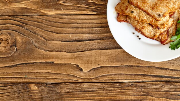 Roast meat in a plate on a wooden table.