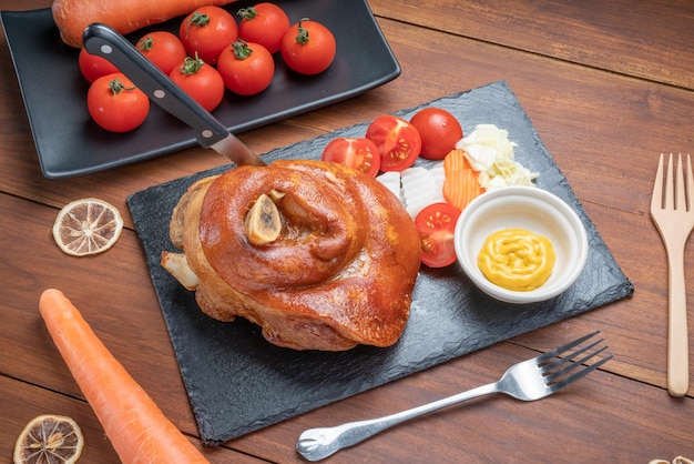 Roast pork leg on hot stone plate Deep fried pork or German Pork Hocks on wooden background