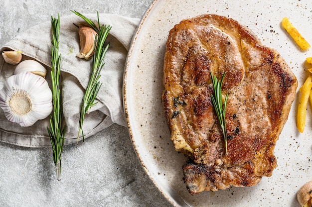 Roast pork steak with French fries. Gray background. Top view