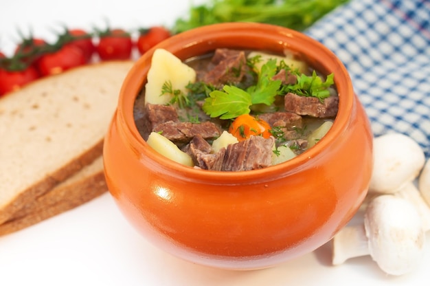 Roast in a pot with beef meat and potatoes on the table