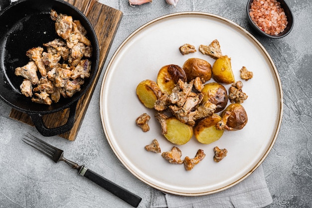 Жареный картофель с лисичками и луком, на фоне серого каменного стола, плоская планировка, вид сверху