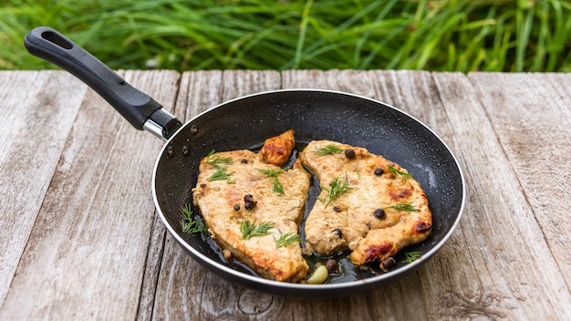 Roast Turkey in a frying pan on a wooden table.