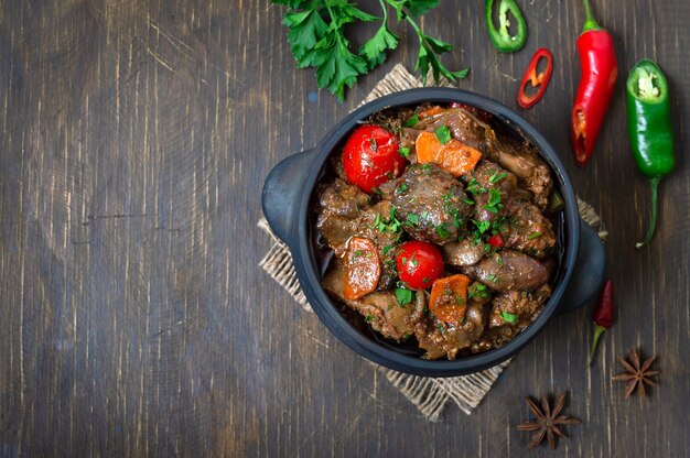 Roast turkey liver with vegetables in a pot. Delicious dietary meal. Rustic style. Top view. Copy space.