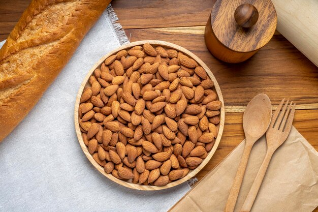 Photo roasted almond on wooden table, almond in wooden plate ready to serve.