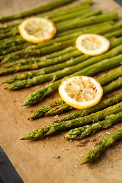 Roasted asparagus and lemon on a baking sheet, vertically. Close-up.