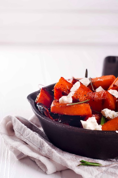 Roasted, baked pumpkin with addition aromatic herbs and goat cheese