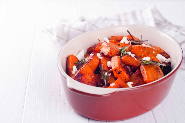 Roasted, baked pumpkin with addition aromatic herbs and goat cheese