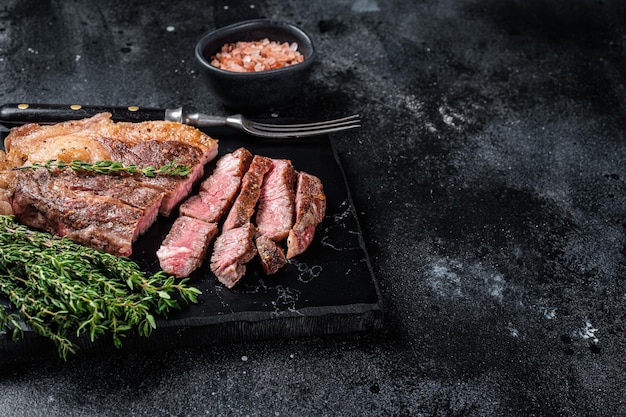 Roasted bbq Chuck Roll beef steaks with herbs Black background Top view Copy space