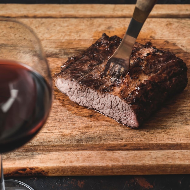 Roasted beef ribs with a glass of red wine presented on the table traditional Argentine cuisine Asado barbecue Patagonia Argentina