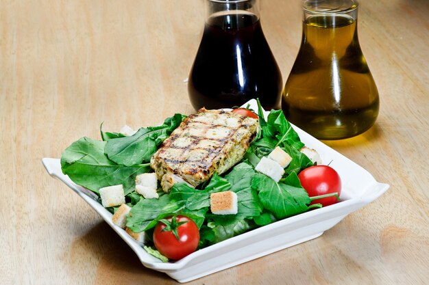 Photo roasted black pepper lamb steak with salads and fries on a blue round plate. wooden texture background.