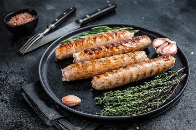 Roasted Bockwurst pork meat sausages in a plate. Black background. Top view.