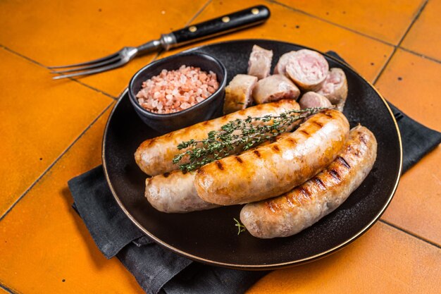 Фото Обжаренные колбасы из свинины bratwurst и bockwurst на тарелке оранжевый фон верхний вид