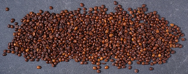 Roasted brown coffee beans on a gray background