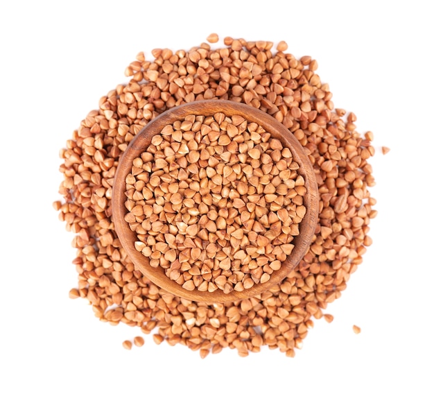 Roasted buckwheat grains in wooden bowl, isolated on white background. Dry brown buckwheat groats. Top view.