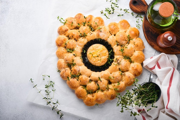 Roasted camembert cheese and homemade bread heart shaped and thyme on rustic background. French cheese. Concept of romantic love for Valentines Day. Top view, copy space.