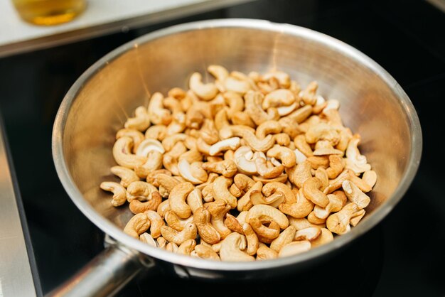 Foto noci di anacardo arrostite in una padella su una stufa elettrica cucinare dolci noci nutrienti che fanno venire l'acqua in bocca