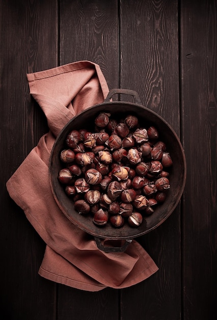 Roasted chestnuts in an iron pan wooden table top view no people rustic style