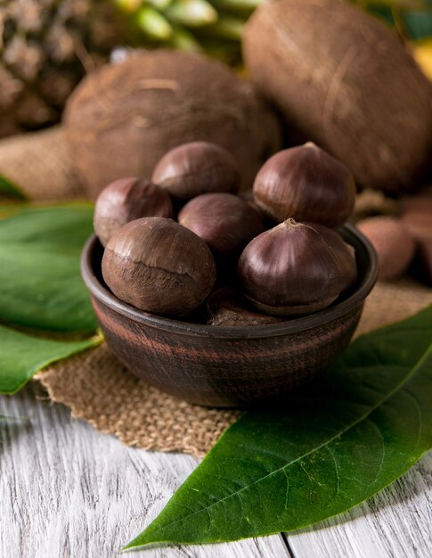 Roasted chestnuts served in chestnut pan onn old table.