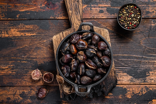 Premium Photo  Roasted chestnuts in a chestnut pan skillet with holes on a  aged brown wooden table