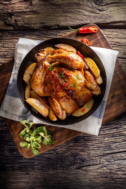 Roasted chicken and american potatoes with chili peppers and herbs - Top of view.