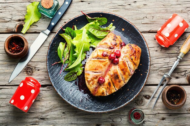 Foto petto di pollo arrosto con salsa di ciliegie. carne di pollo al forno con frutti di bosco su fondo di legno rustico