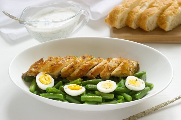 Roasted chicken breasts served with fried egg and boiled green beans.