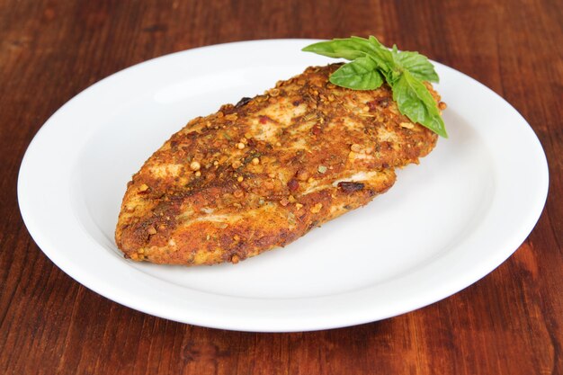 Roasted chicken fillets on white plate on wooden background