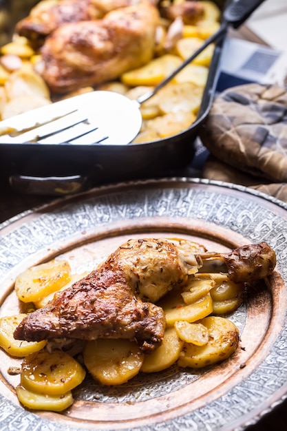 Photo roasted chicken leg with potatoes with caraway and garlic.