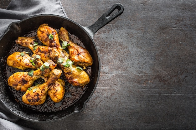 Roasted chicken legs in pan with herbs - close up.