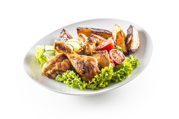 Roasted chicken legs with lettuce salad potatoes and tomatoes isolated on white.