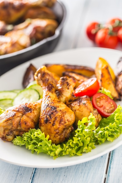 Roasted chicken legs with lettuce salad and tomatoes.