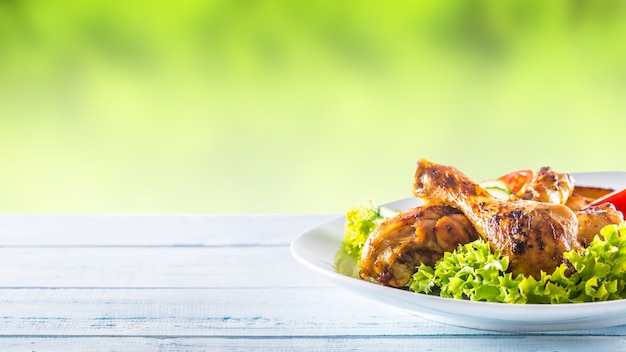 Roasted chicken legs with lettuce salad and tomatoes.